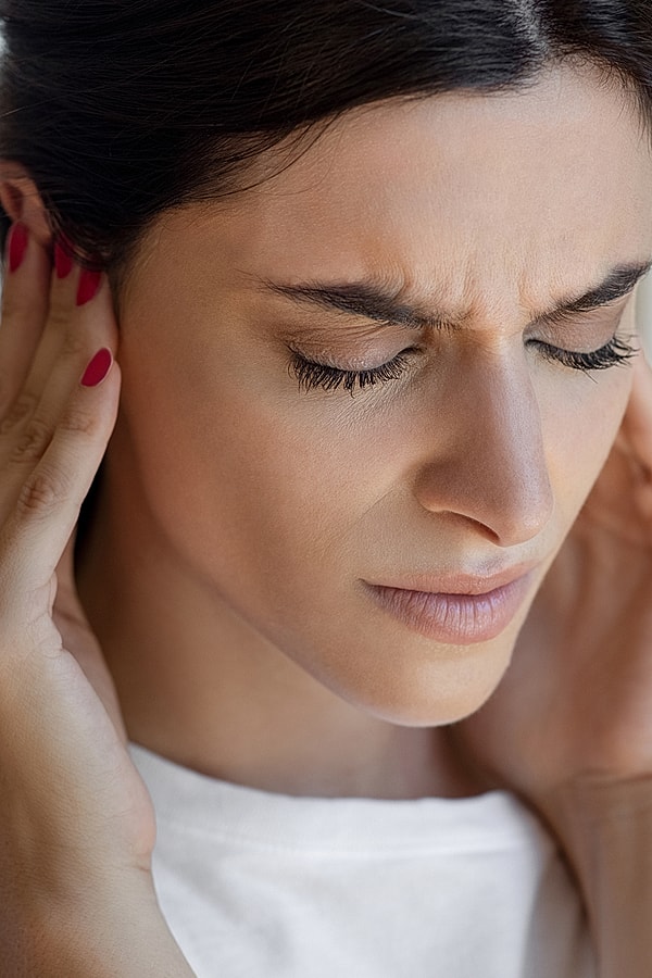 Person holding their ear in discomfort.