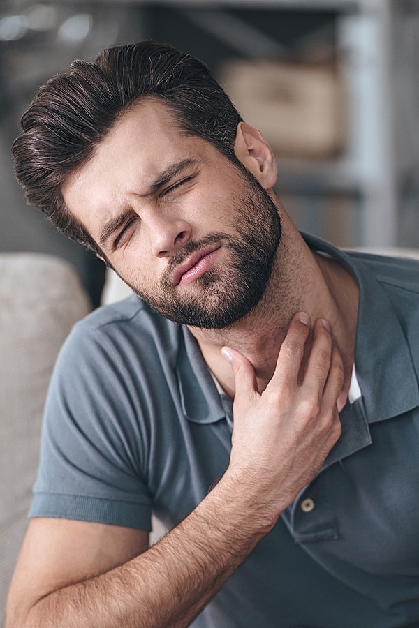 Man with sore throat looking uncomfortable.