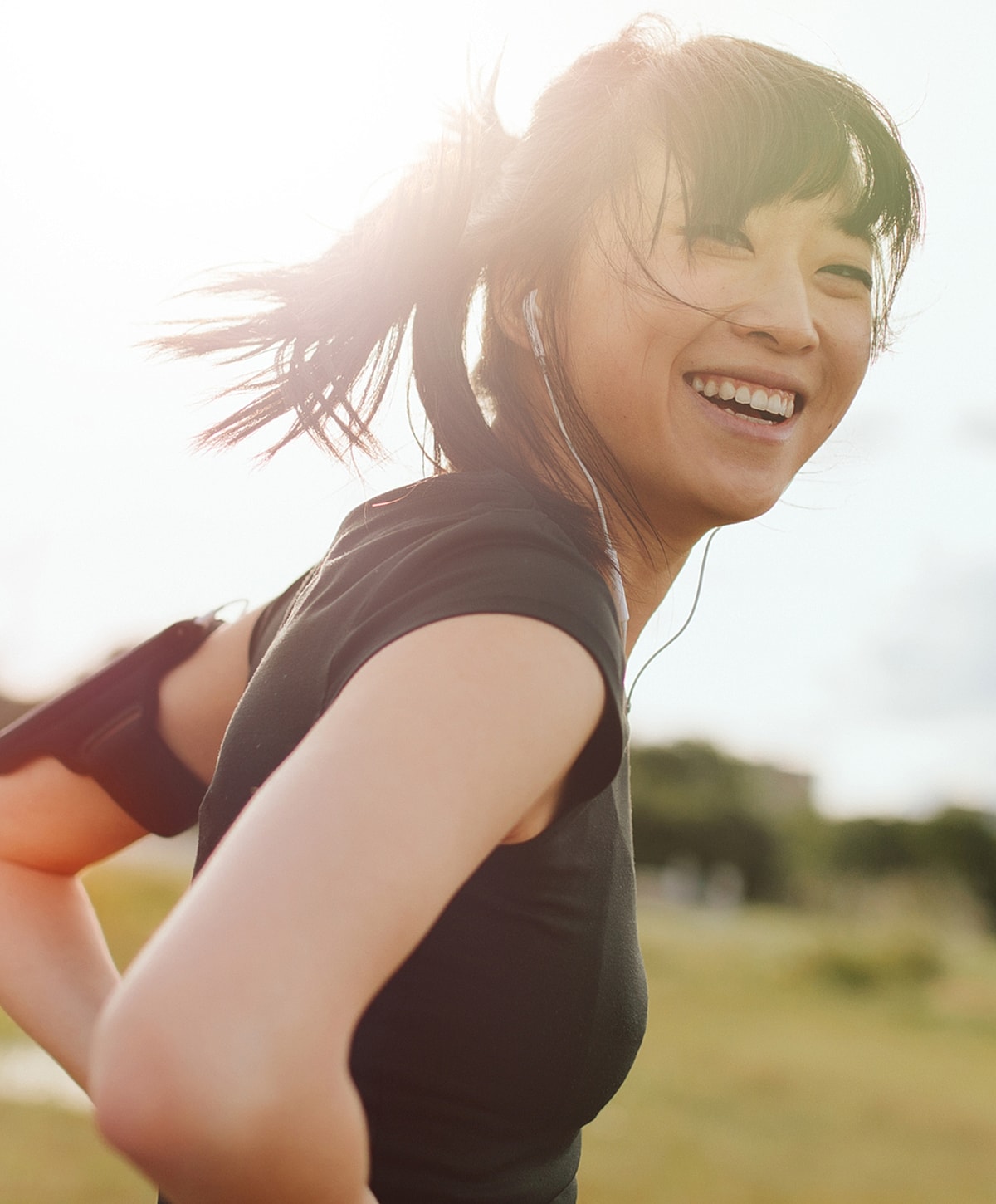 Smiling woman running outdoors with headphones.