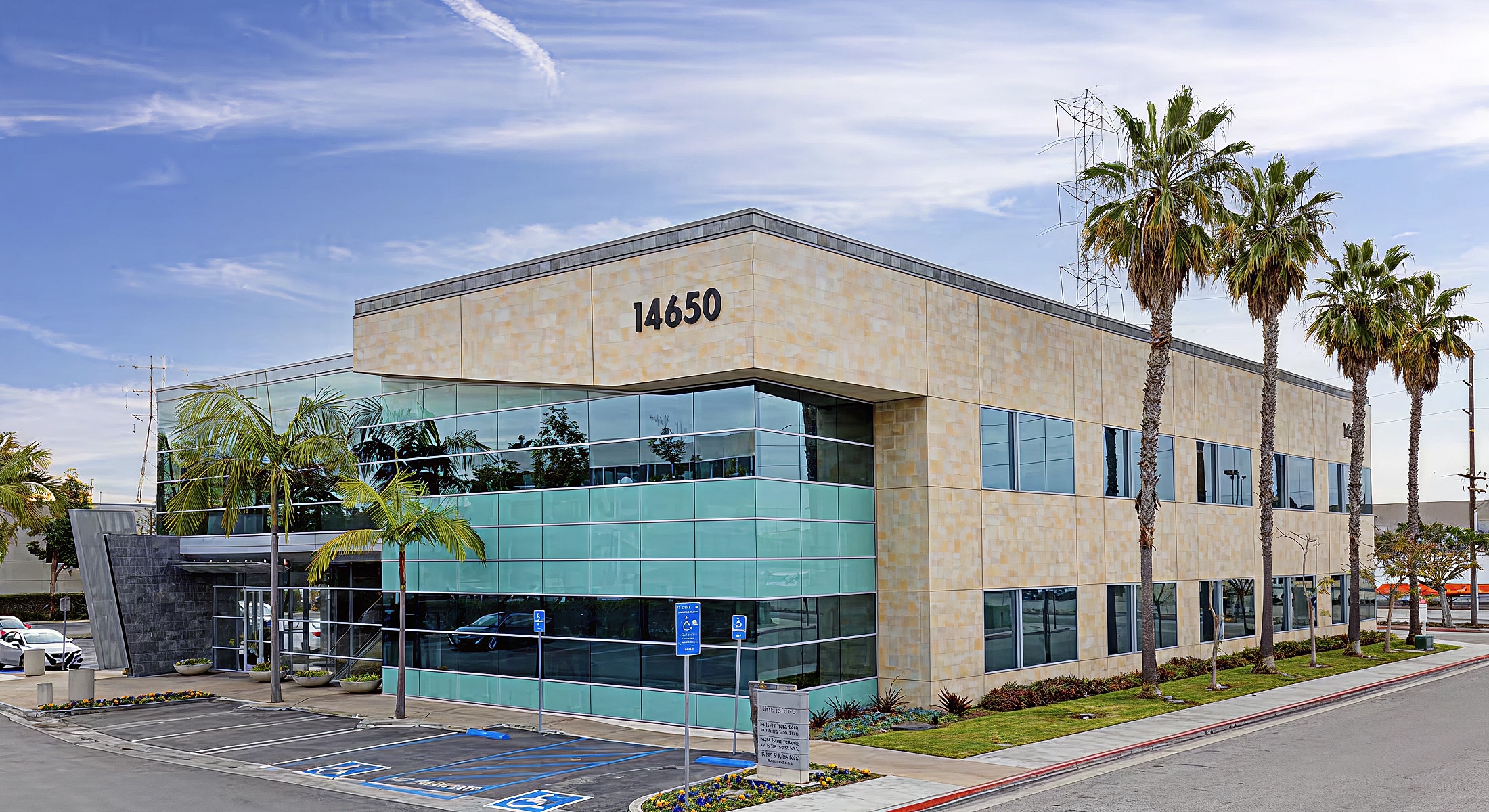 Modern office building with palm trees and signage.