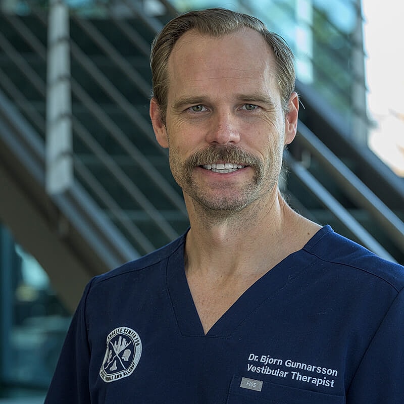 Male therapist smiling in medical scrubs.