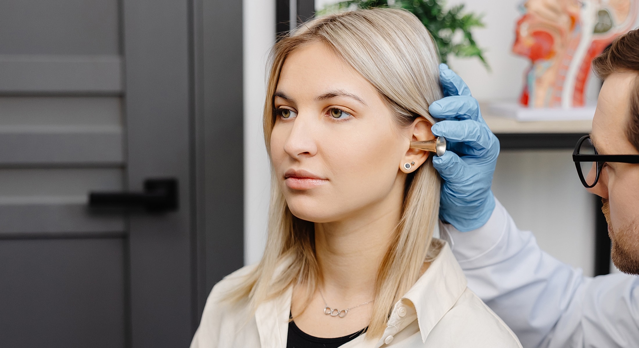 Doctor examining patient's ear with otoscope.