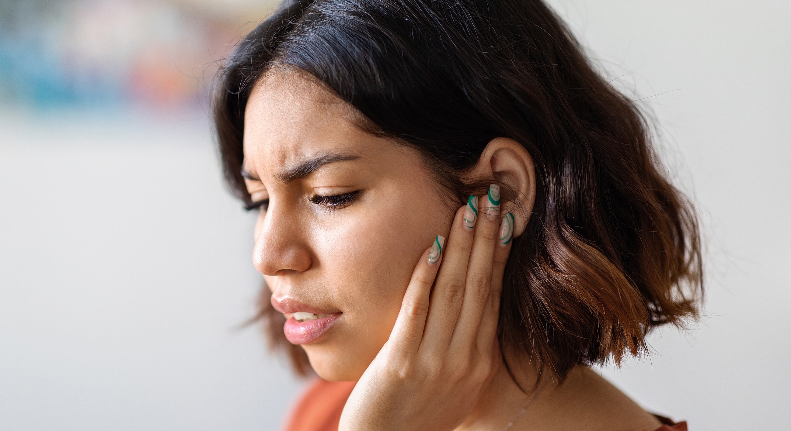 Woman touching her ear with a pained expression.