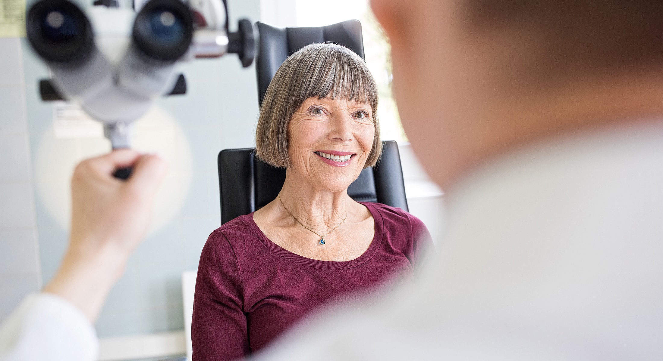 Doctor examining older woman's neck in clinic.
