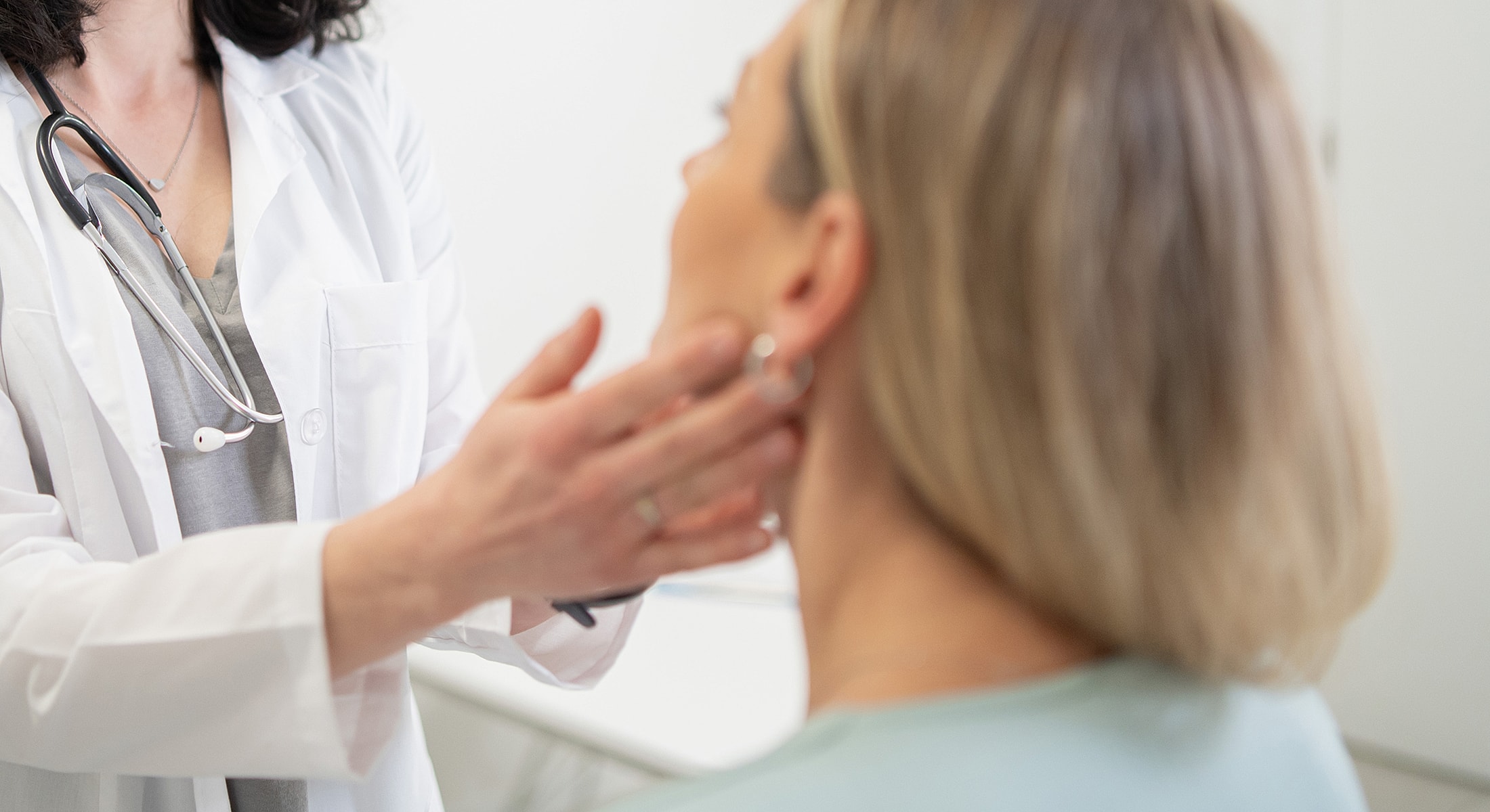 Doctor examining patient's neck in a clinic.