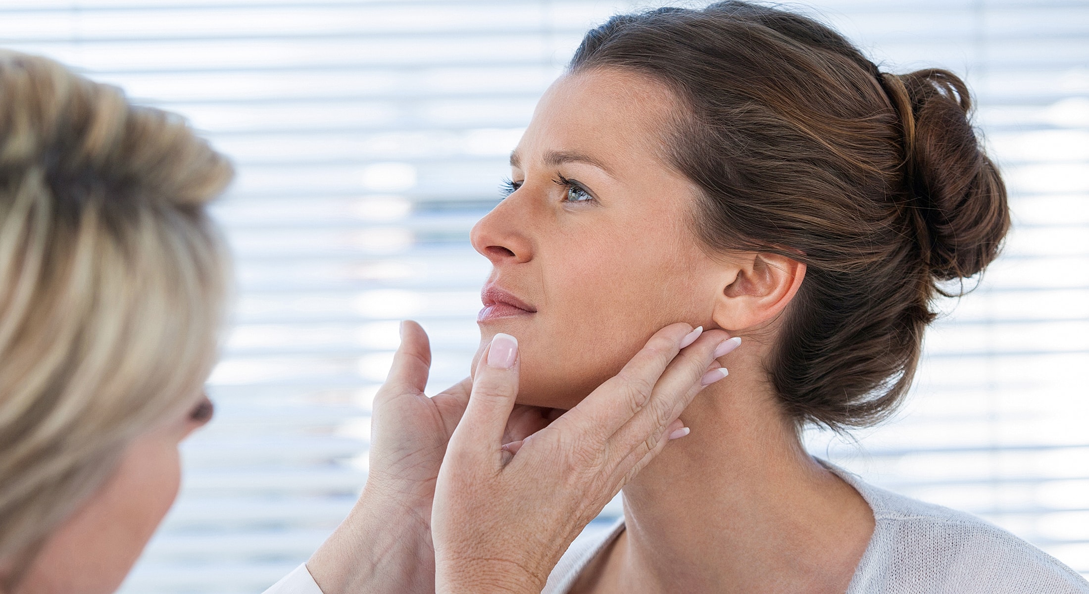 Woman receiving facial treatment in bright setting.