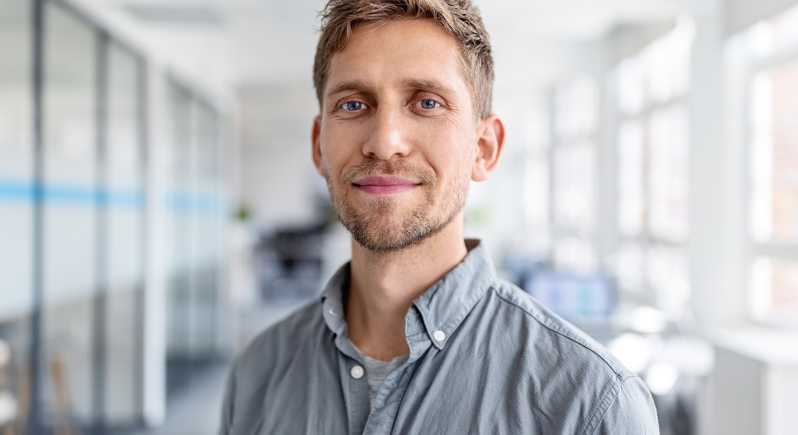 Smiling man in office environment with natural light.