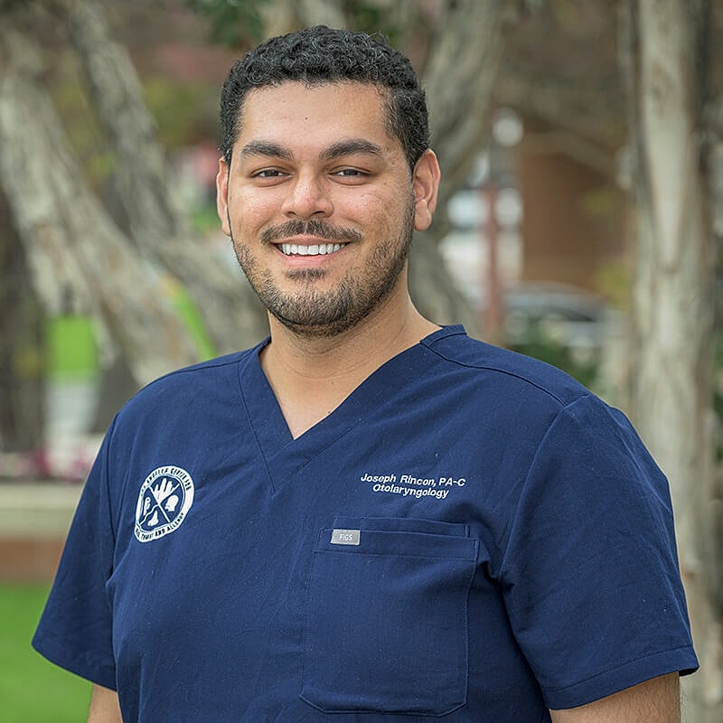 Healthcare professional smiling in outdoor setting.