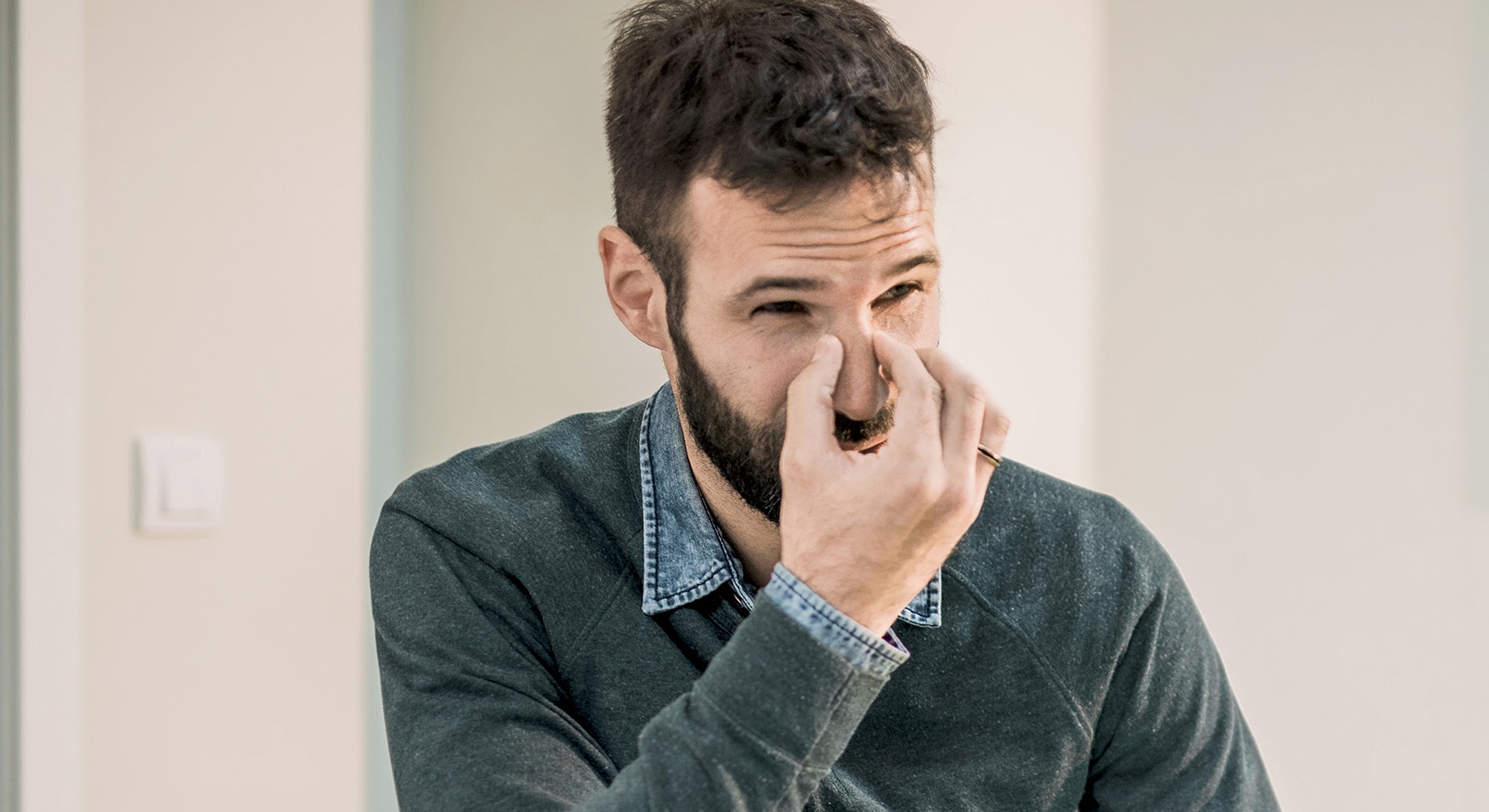 Man touching his nose with a pained expression.