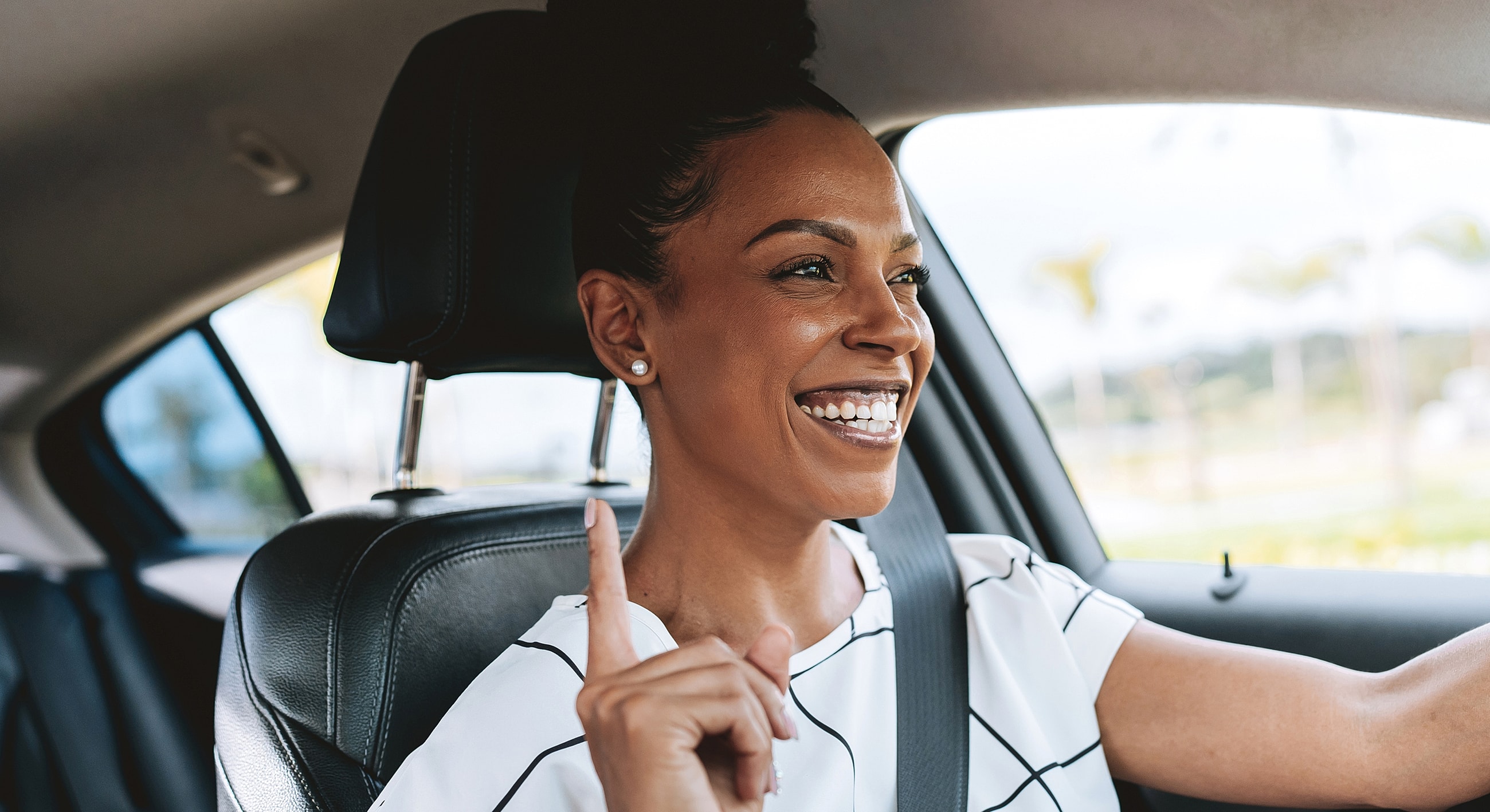 Smiling woman driving a car, enjoying the moment.