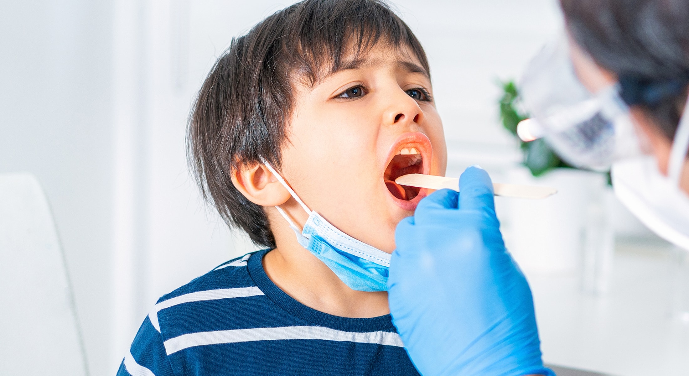 Doctor examining patient's neck in medical office.
