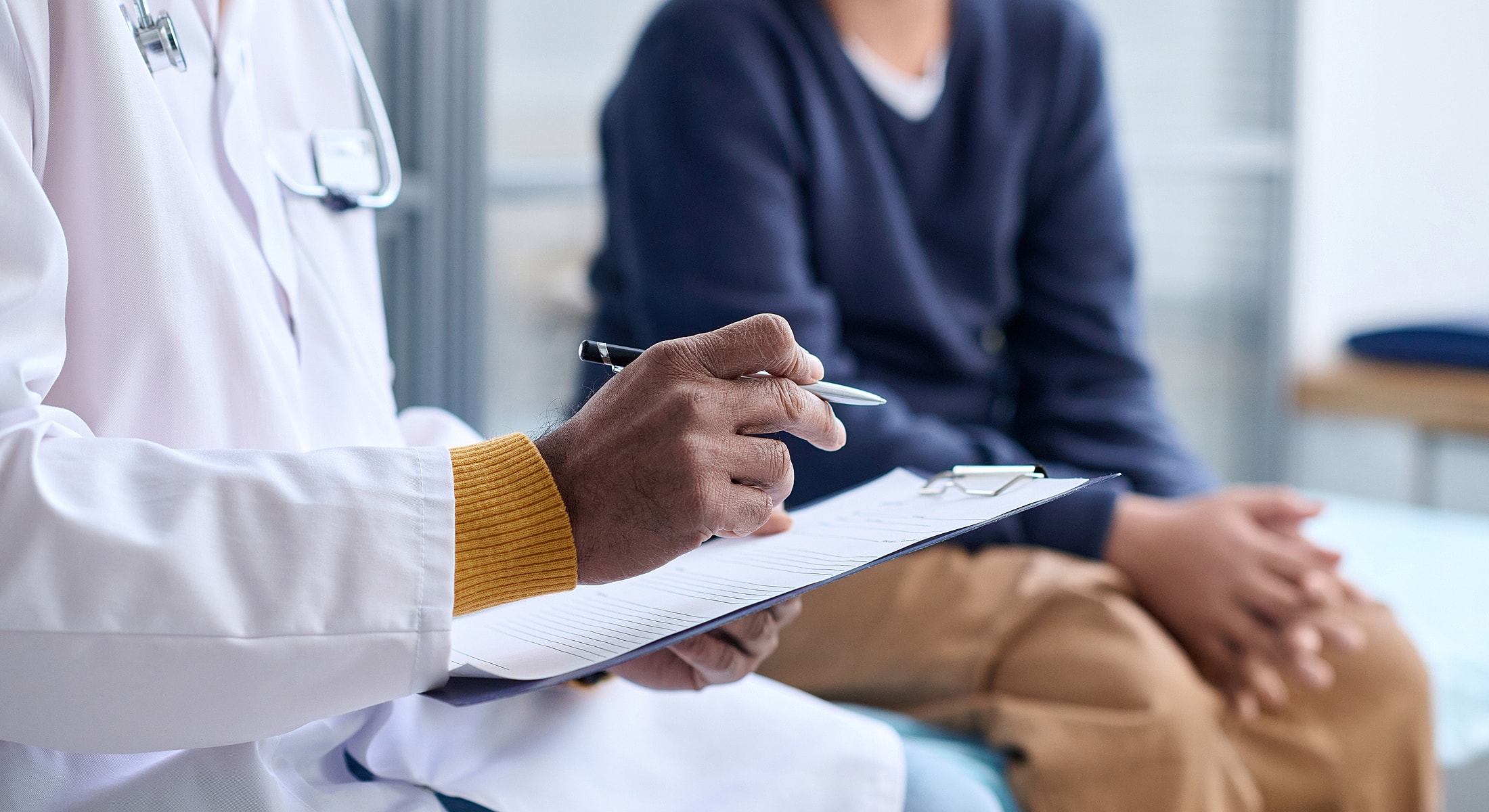Doctor taking notes during patient consultation.