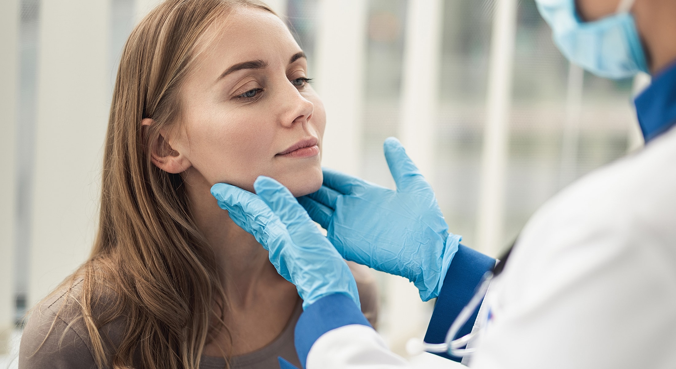 Medical professional examining a woman's face carefully.