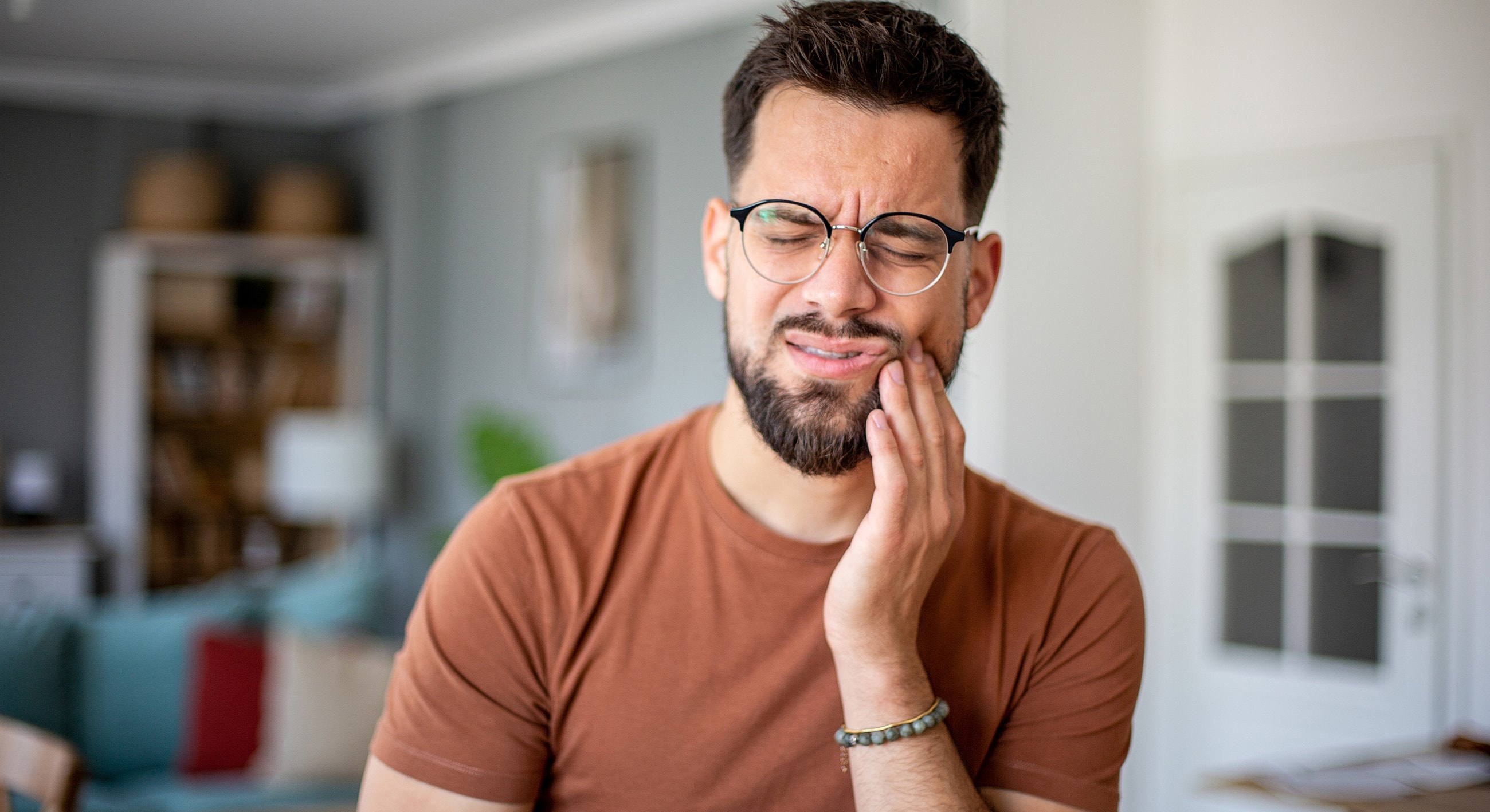Man experiencing tooth pain at home.